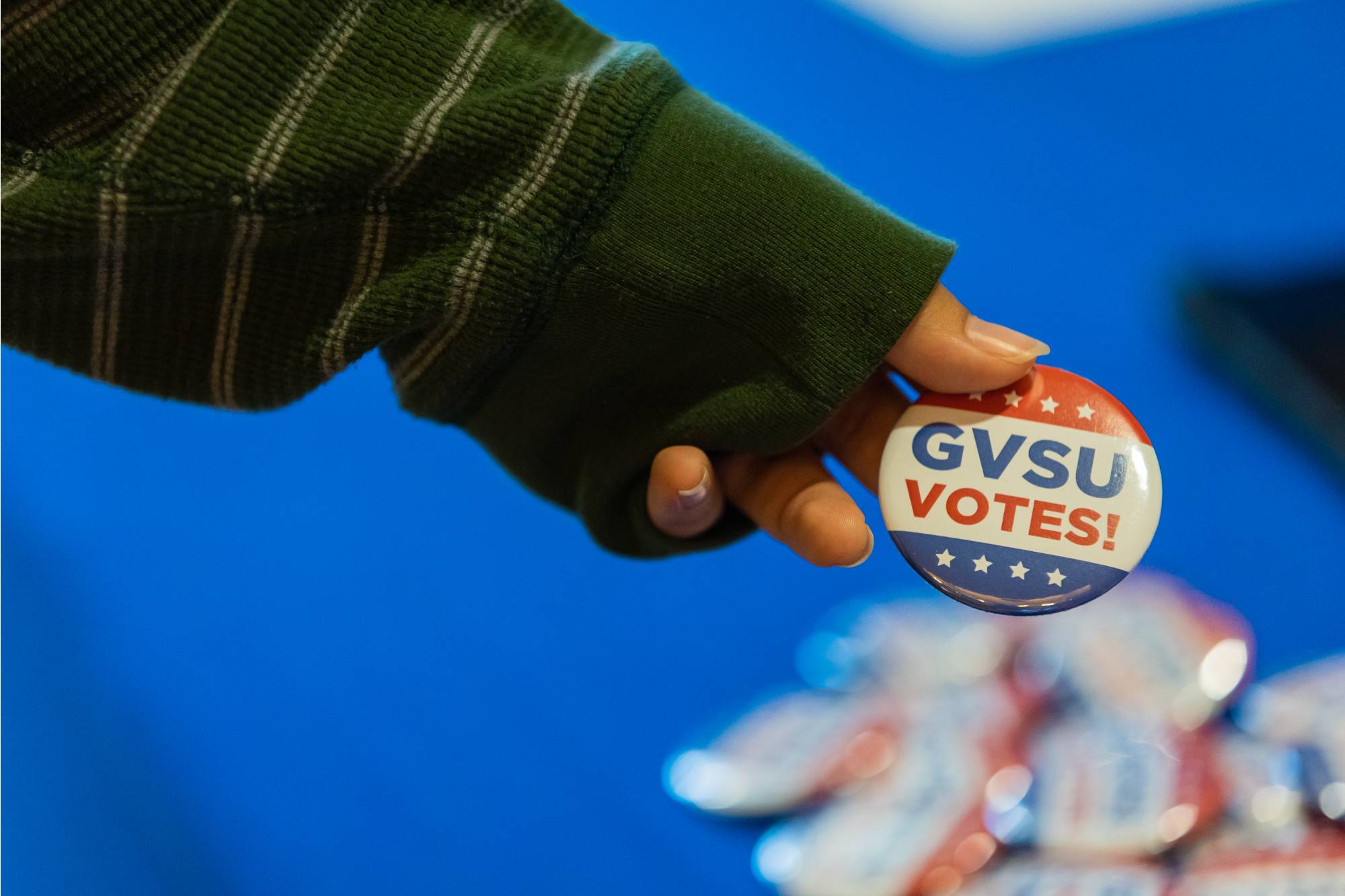 a hand holding a GVSU votes button
